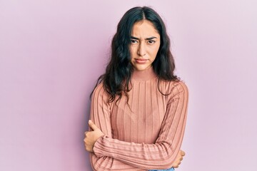 Hispanic teenager girl with dental braces wearing casual clothes skeptic and nervous, disapproving...