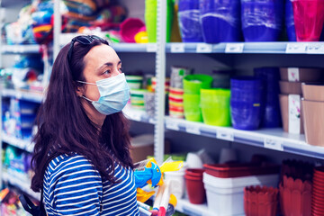 Woman in medical mask choosing goods in a store. Concept of shopping during quarantine at covid-19...