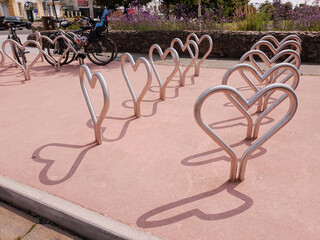 The bicycle parking station in Greystones town, Ireland. Rows of metal heart shaped racks. Local  park in the background. Sunny summer day.