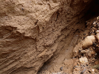 Sandy wall eroded by flowing water. Coastal erosion.