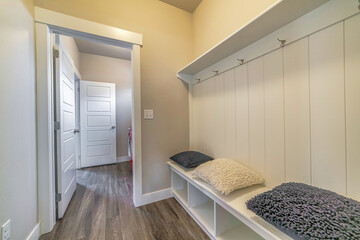 Mud room interior of a house with hooks shelves and built in bench with pillows