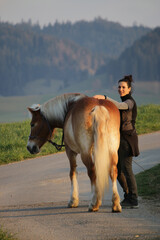Woman caresses dressage horse on rural road