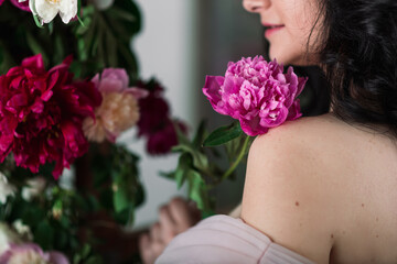 Fototapeta premium Indoor studio shot of sweet adorable young woman with white,pink and purple flowers in hands.
