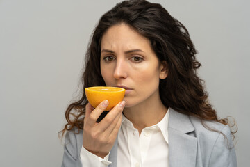 Sick business woman trying to sense smell of half fresh orange, has symptoms of Covid-19, corona...
