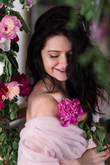 Indoor studio shot of sweet adorable young woman with white,pink and purple flowers in hands.