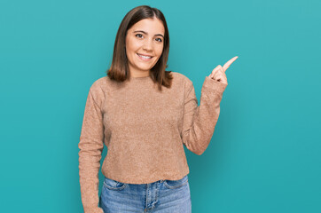 Young beautiful woman wearing casual clothes cheerful with a smile on face pointing with hand and finger up to the side with happy and natural expression