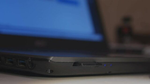 Safely remove hardware. A man's hand extracts a SD card with information from a laptop.