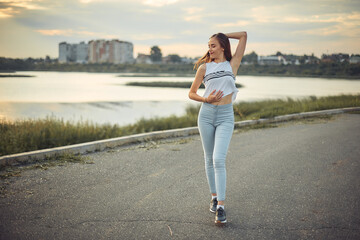 Young beautiful caucasian blonde girl listening to music with smartphone walking and dance in the...