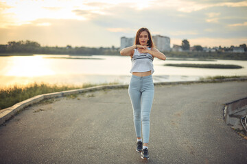Young beautiful caucasian blonde girl listening to music with smartphone walking and dance in the...