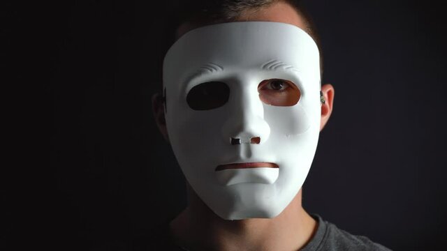 a man hides his face under a white mask