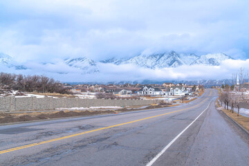 Highway along Utah Valley community with Wasatch Mountain and dense clouds view