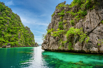 Naklejka na ściany i meble Blue crystal water in paradise Bay with boats on the wooden pier at Kayangan Lake in Coron island, tropical travel destination - Palawan, Philippines.