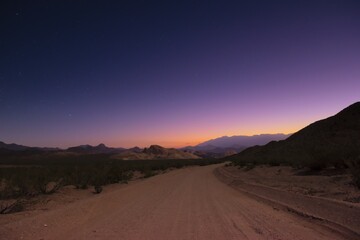 Dirt road into the unknown under a starry twilight sky.