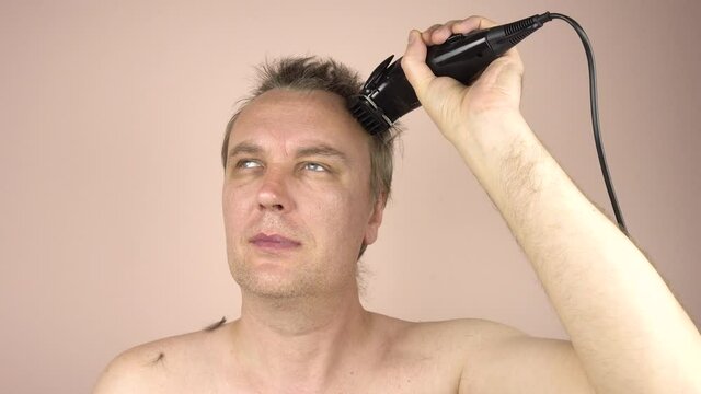 A Grown Man With Blond Hair Gets His Haircut With A Clipper.Men's Haircut At Home During Self-isolation Due To The Covid 19 Pandemic.