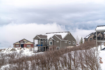 Homes on hill top covered with snow in winter against background of cloudy sky