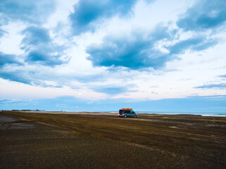 beach with cloudy sky and van with kayak