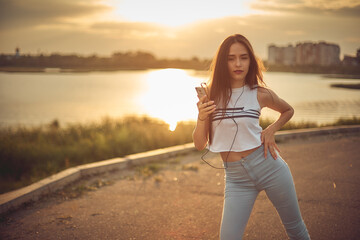 Young beautiful caucasian girl listening to music with smartphone walking in the city with headphones smiling - relax, youth, emancipation concept