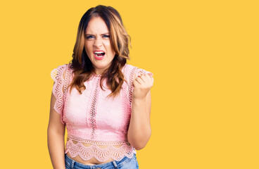 Young beautiful caucasian woman wearing casual clothes angry and mad raising fist frustrated and furious while shouting with anger. rage and aggressive concept.