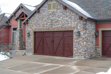 Garage entrance of home with combination of stone and red wood on exterior wall