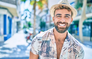 Young hispanic man on vacation smiling happy walking at street of city
