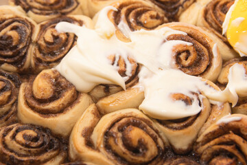 freshly baked cinnabons with cinnamon and buttercream on parchment paper.