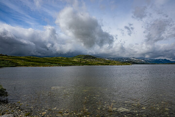 Lake with mountains and green land around it