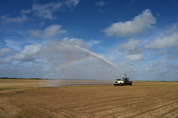 Fototapeta na wymiar Pump truck irrigating planted fields near Homestead, Florida creating rainbow in spray on sunny winter morning.