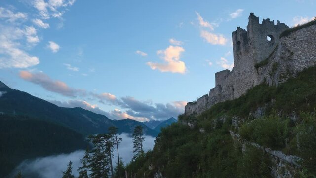 Timelapse of Ehrenberg Castle ruins at sunset, with fog in the valley below. Touristic landmark in Reutte, Tyrol, Austria.