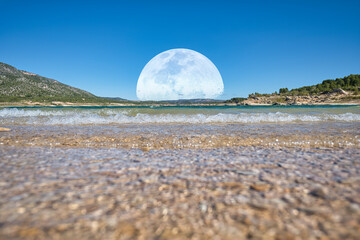saliendo la luna sobre las monta&ntilde;as y el agua 