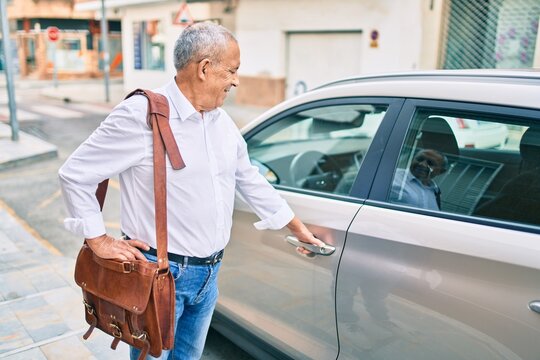 Senior man smiling happy opening car at the city.