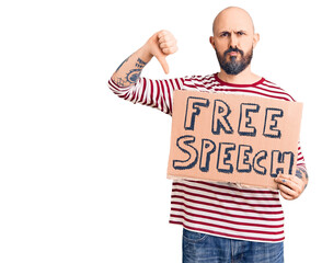 Young handsome man holding free speech banner with angry face, negative sign showing dislike with...