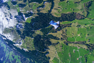Wingsuit flier glides over snowcapped mountains