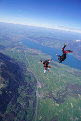 Skydivers perform tricks above snowcapped mountains
