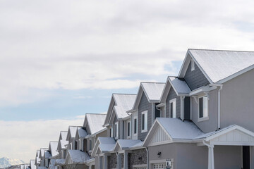 Townhouses with snowy gable roofs in winter on a scenic suburbs community. - obrazy, fototapety, plakaty