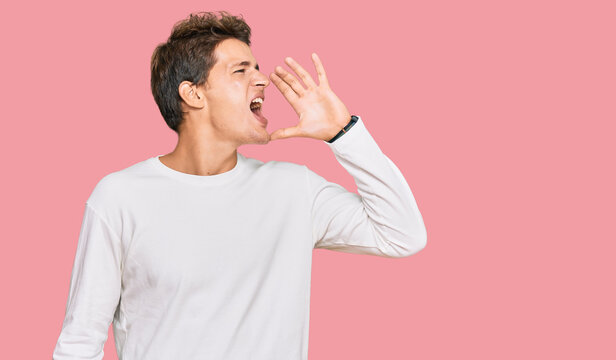 Handsome caucasian man wearing casual white sweater shouting and screaming loud to side with hand on mouth. communication concept.