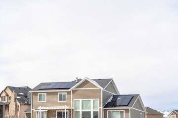 Houses in Utah Valley with solar panels on roofs against cloudy sky in winter
