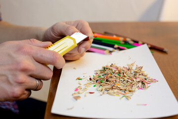 A man sharpens a pencil with a stationery knife