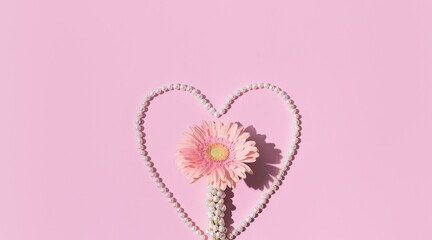 Beautiful gerbera flower with white pearl necklace on pastel pink background