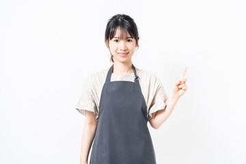 人差し指でポイントを示すエプロンを着た若い女性