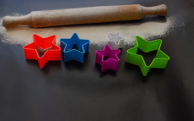 Baking gingerbread on a black background. Flour, rolling pin and cookie molds. Flat styling style