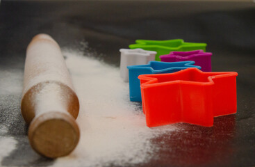 Baking gingerbread on a black background. Flour, rolling pin and cookie molds. Flat styling style