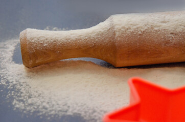 Fototapeta na wymiar Rolling pin and white flour on a dark background. Cooking
