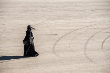 plague doctor alone on a large paved area