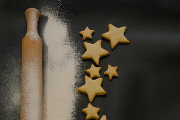 flour and Christmas cookies on a dark background