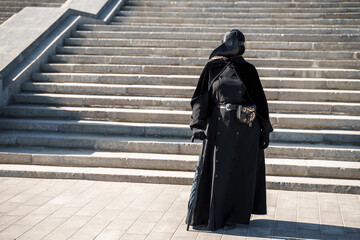 plague doctor in front of the stairs to the top