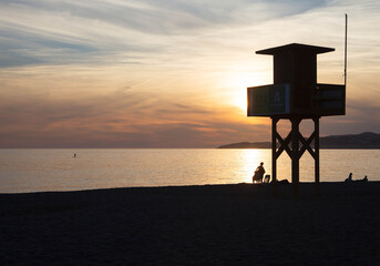 Silhouette of lifeguard tower on beach at sunset