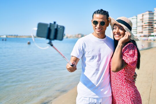 Young latin couple smiling happy making selfie by the smartphone at the beach.