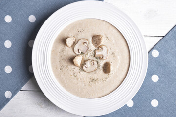 Creamy chicken soup with mushrooms on a white plate.