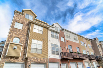 Fototapeta premium Front view of three storey townhouses with balconies and attached garage