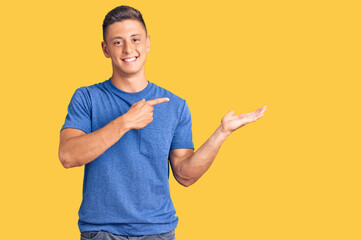 Young handsome hispanic man wearing casual clothes amazed and smiling to the camera while presenting with hand and pointing with finger.